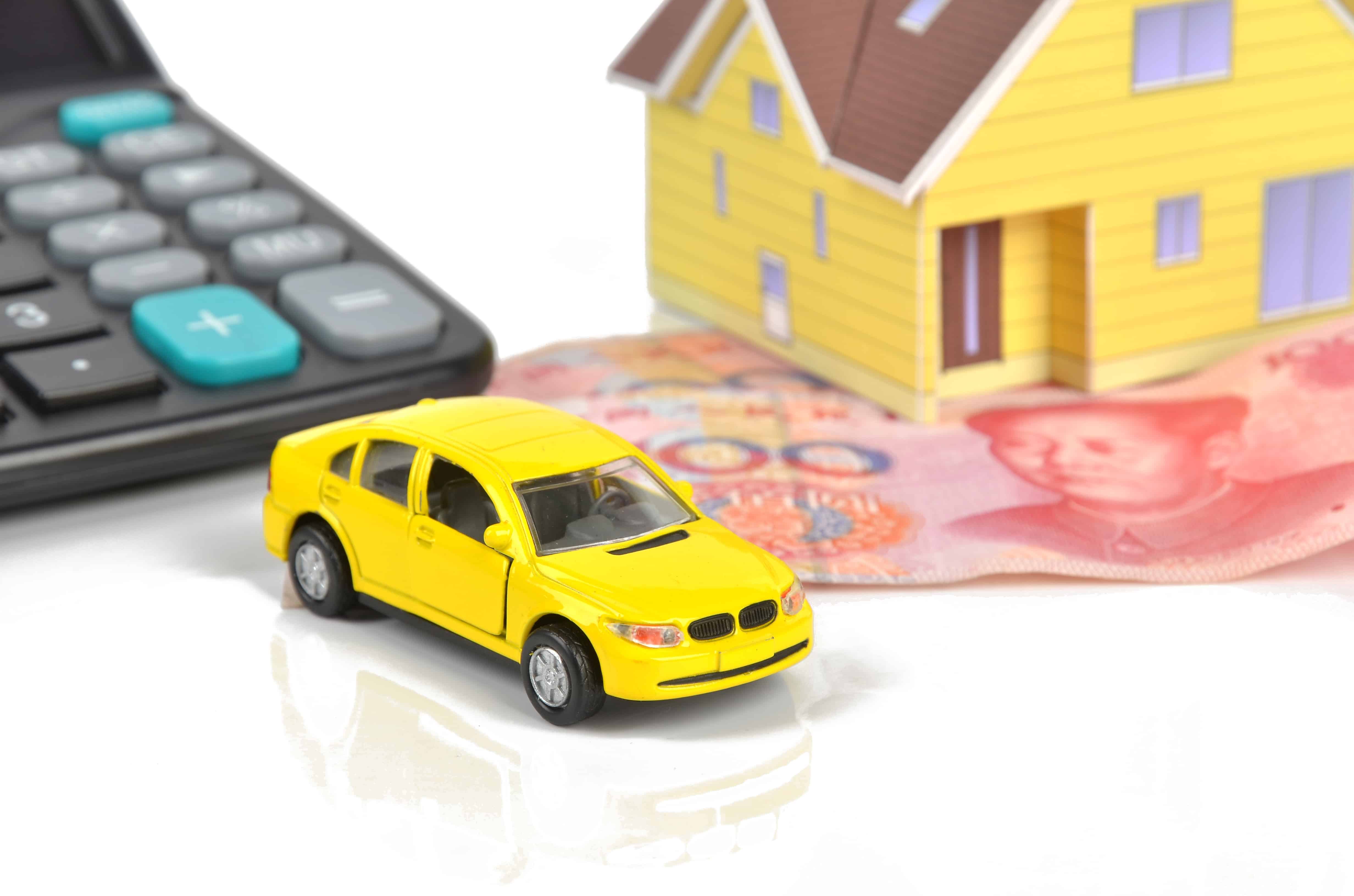 Miniature car and house next to a calculator and currency notes, representing financial planning for home first trial expenses.