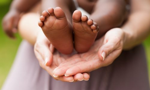 How Parents cradling a baby's bare feet, selected through overseas adoption.