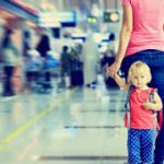 A parent holding hands with two young children at an airport terminal, navigating Legal Self-Representation.